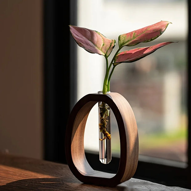 Wooden vase with a clear base holding pink leaves on a blurred background